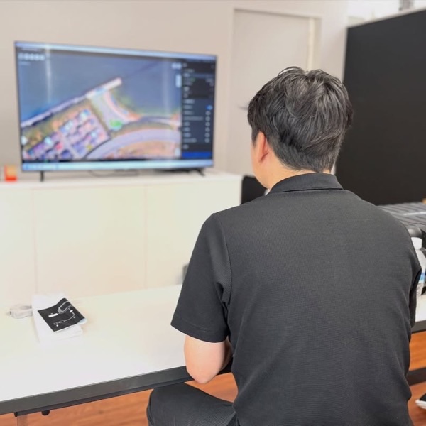 店内で、大型モニターに映したドローンの操作画面を見ながら「DJI Matrice 4T」の講習を受けるお客様の後ろ姿