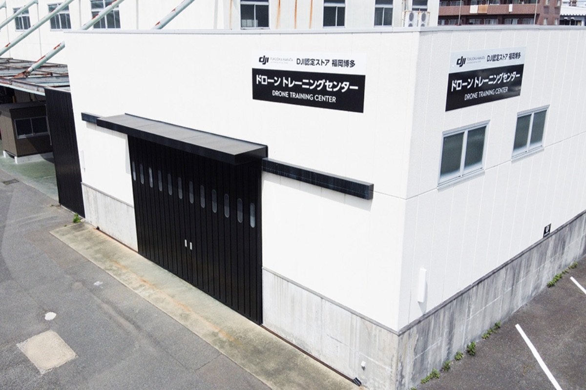 ドローン・トレーニングセンターの外観。「DJI認定ストア 福岡博多 ドローントレーニングセンター」の看板が掲げられた白い建物